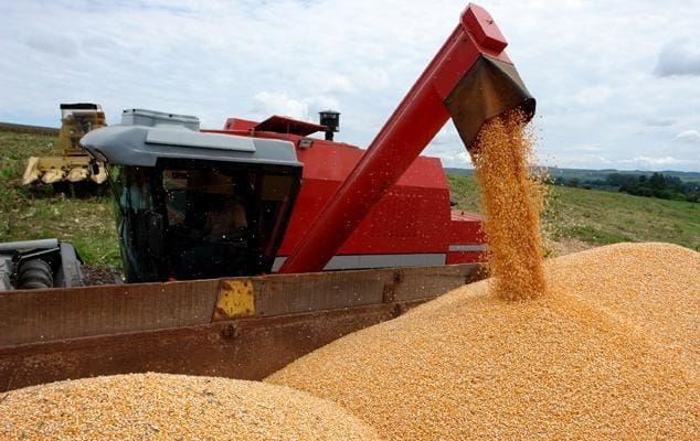 foto de colheitadeira de milho despejando grãos em caminhão