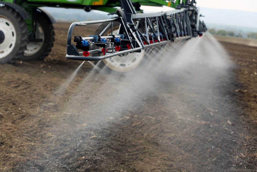 Imagem de máquina agrícola despejando defensivo em solo