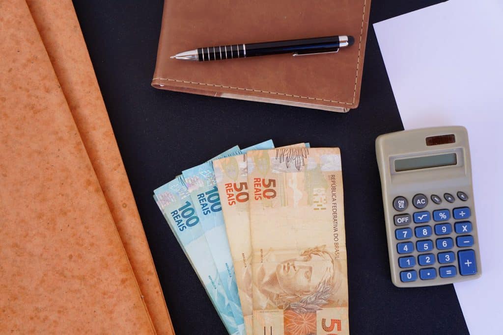 títulos de crédito do agronegócio: imagem de notas de 50 e 100 reais, calculadora e caderno de anotações com caneta