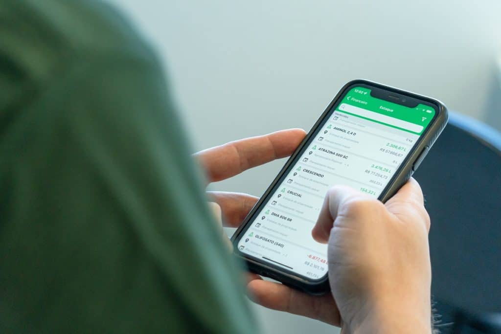 Foto de mãos de um homem segurando um celular, com o app do Aegro aberto