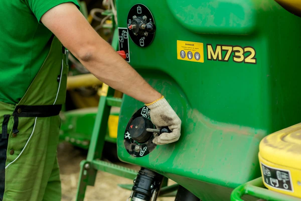 Homem fazendo manutenção em um trator verde