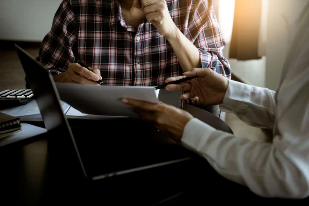 Foto de pessoas reunidas em uma mesa, analisando um computador