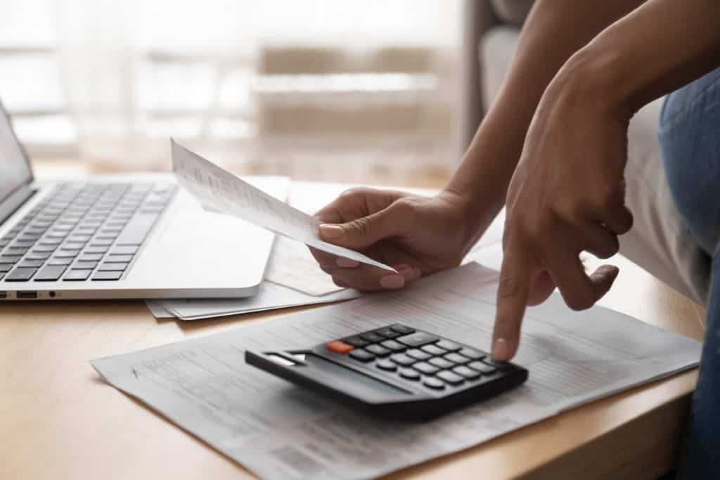 Pessoa calculando sobre uma mesa, olhando algumas contas
