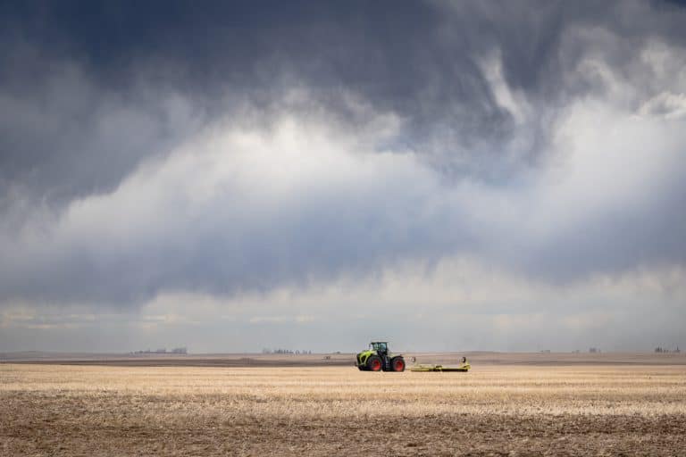 Foto de trator agrícola em fazenda, com céu carregado ne nuvens e prestes a chover