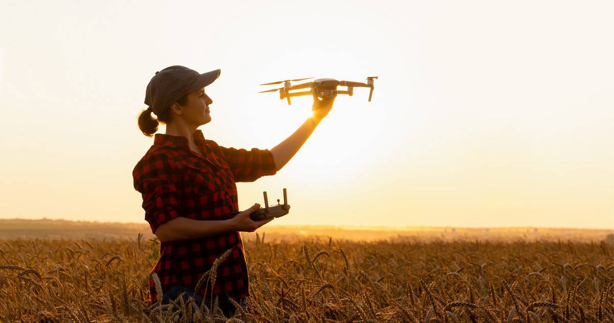mulher segurando drone no campo
